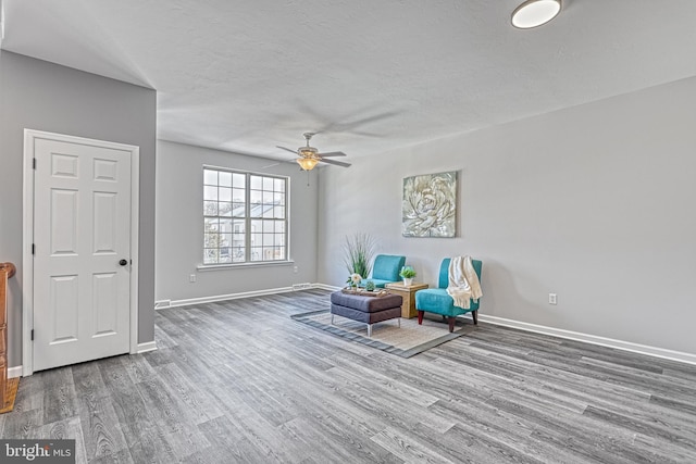 living area featuring ceiling fan, hardwood / wood-style flooring, and a textured ceiling