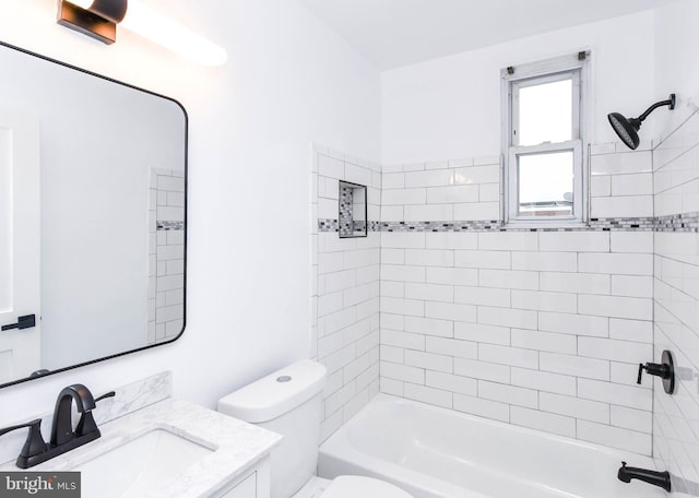 full bathroom featuring vanity, tiled shower / bath, and toilet