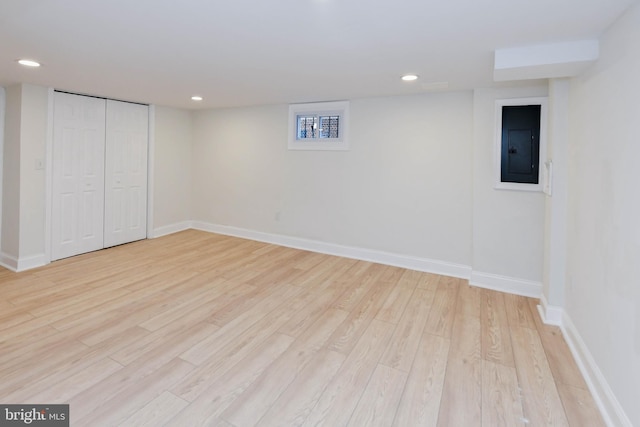 basement featuring electric panel and light wood-type flooring