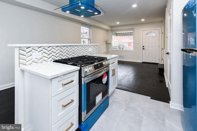 kitchen featuring white cabinetry, gas range, light stone counters, and decorative backsplash