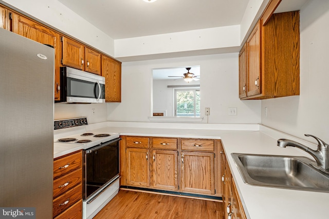 kitchen with sink, stainless steel appliances, ceiling fan, and light wood-type flooring