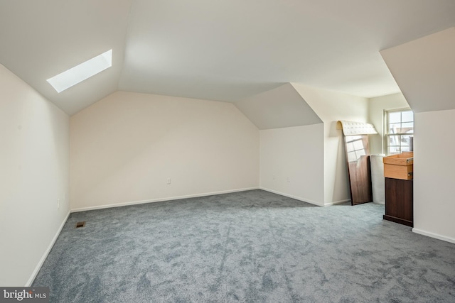 additional living space with carpet flooring and lofted ceiling with skylight