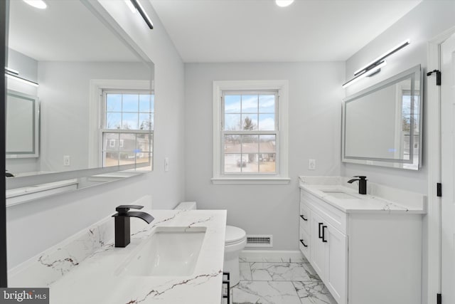 bathroom with plenty of natural light, toilet, and vanity