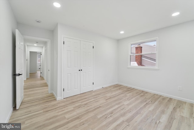 unfurnished bedroom with a closet and light wood-type flooring