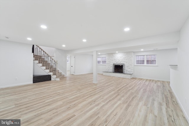 unfurnished living room featuring a stone fireplace and light hardwood / wood-style flooring