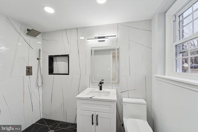 bathroom with vanity, tile walls, walk in shower, and toilet