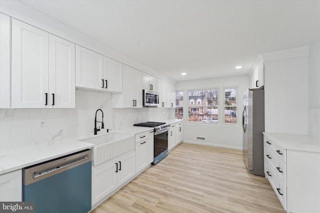 kitchen with sink, light stone counters, stainless steel appliances, decorative backsplash, and white cabinets