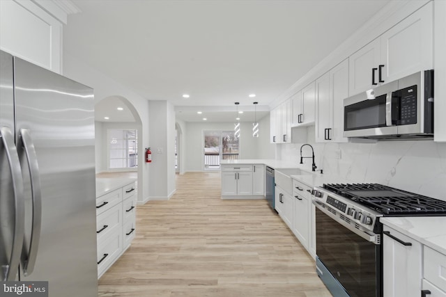 kitchen featuring sink, white cabinetry, hanging light fixtures, kitchen peninsula, and stainless steel appliances