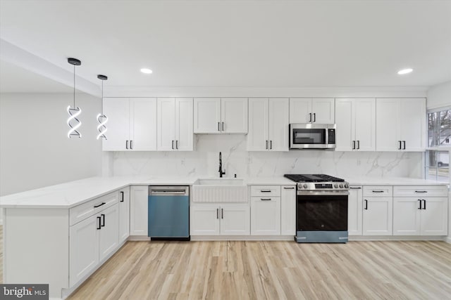 kitchen with white cabinetry, light hardwood / wood-style flooring, appliances with stainless steel finishes, kitchen peninsula, and pendant lighting