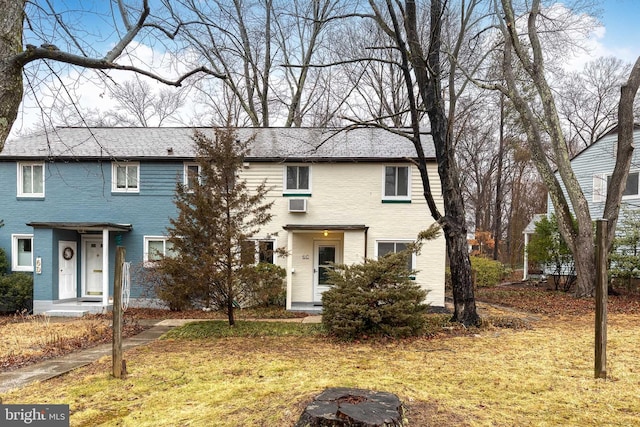 view of front of property with a wall unit AC and a front yard