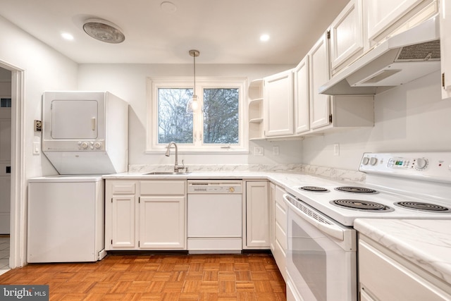 kitchen with white appliances, stacked washer and clothes dryer, and white cabinets