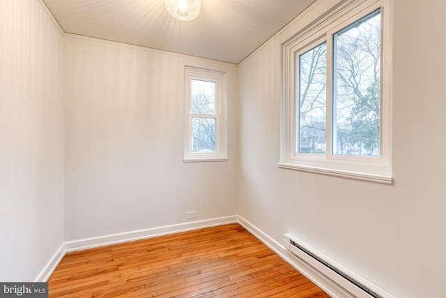 spare room with a baseboard heating unit and light wood-type flooring