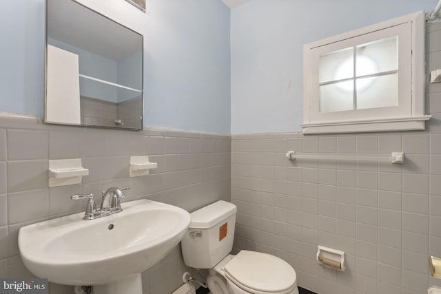 bathroom featuring sink, tile walls, and toilet