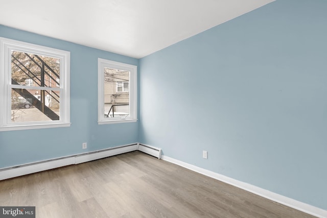 empty room with a baseboard radiator and light hardwood / wood-style flooring