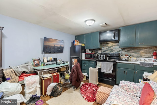 kitchen with tasteful backsplash, radiator heating unit, hardwood / wood-style floors, and black appliances