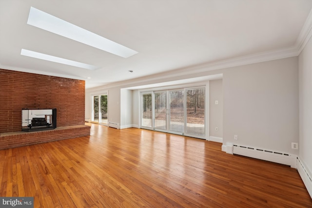 unfurnished living room with crown molding, a skylight, a brick fireplace, and light wood-type flooring