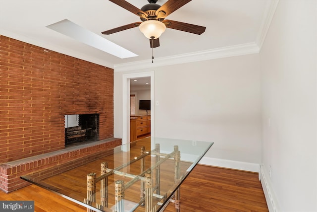 unfurnished dining area with crown molding, brick wall, wood-type flooring, and a brick fireplace