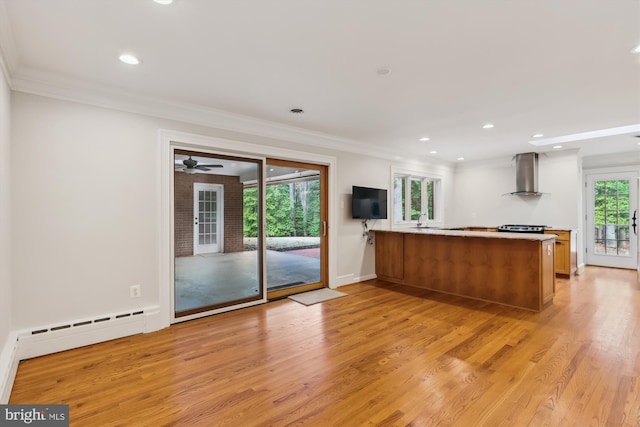 kitchen with a baseboard radiator, ornamental molding, kitchen peninsula, wall chimney range hood, and light hardwood / wood-style flooring