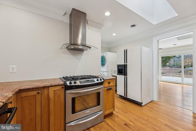 kitchen with stacked washer and clothes dryer, island range hood, light hardwood / wood-style flooring, ornamental molding, and white appliances