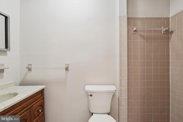 bathroom featuring vanity, toilet, and tiled shower