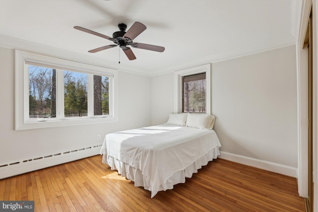 bedroom featuring wood-type flooring, crown molding, ceiling fan, and baseboard heating