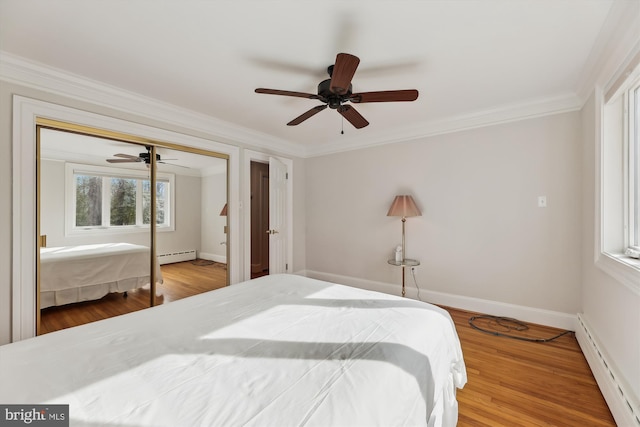 bedroom featuring a closet, ornamental molding, wood-type flooring, and a baseboard heating unit