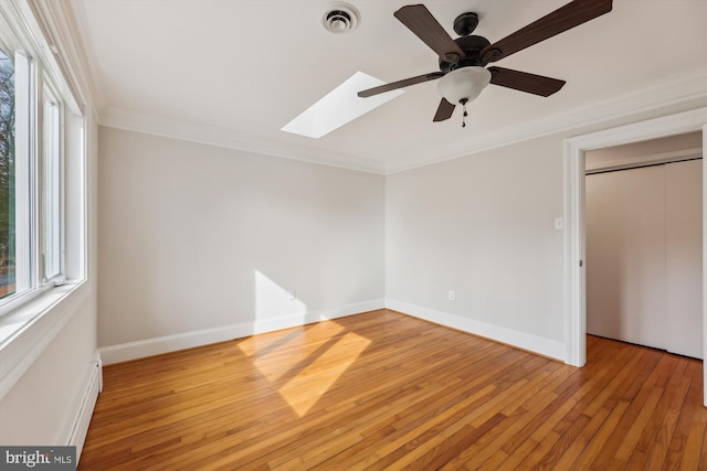 unfurnished bedroom with crown molding, ceiling fan, light wood-type flooring, and a skylight