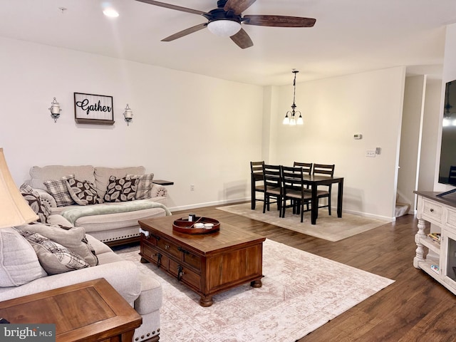 living room with hardwood / wood-style floors and ceiling fan with notable chandelier