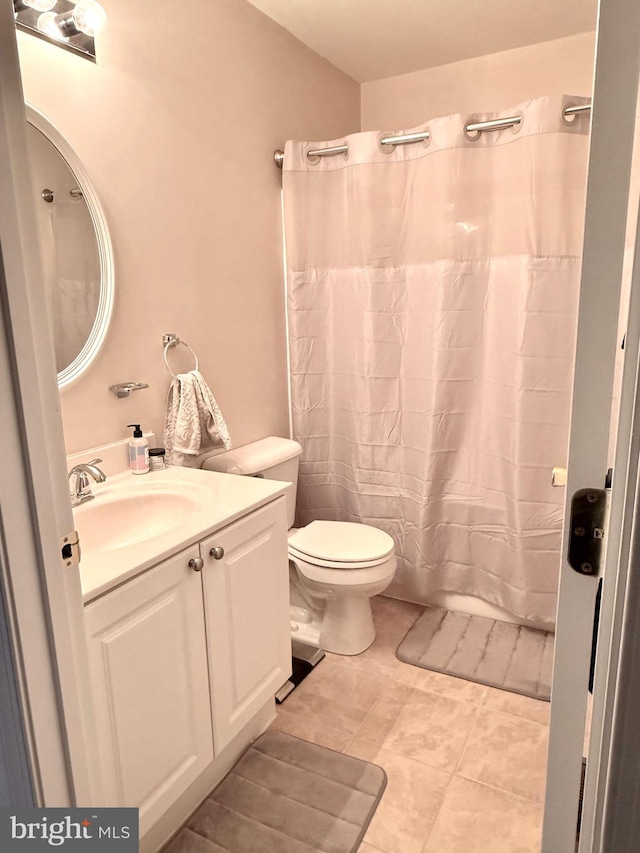 bathroom with a shower with shower curtain, vanity, toilet, and tile patterned flooring