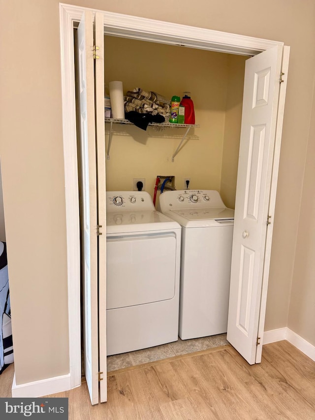 laundry area with separate washer and dryer and light wood-type flooring