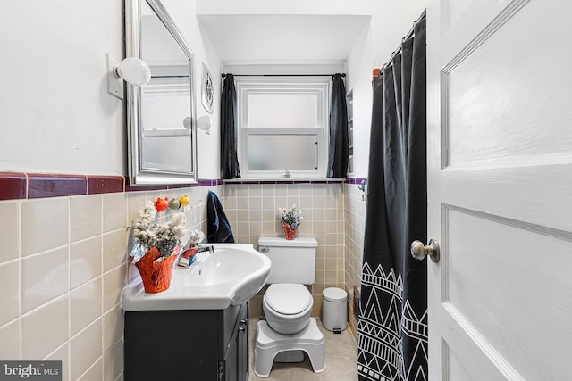 bathroom featuring vanity, tile walls, and toilet