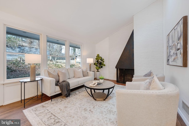 living room with a large fireplace, light wood finished floors, and baseboards