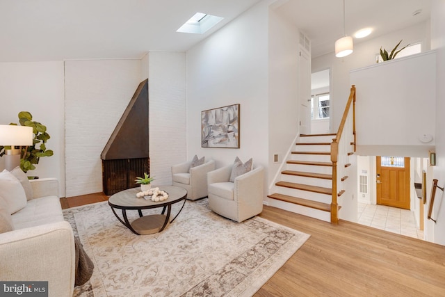 living area featuring a skylight, a high ceiling, stairway, and wood finished floors