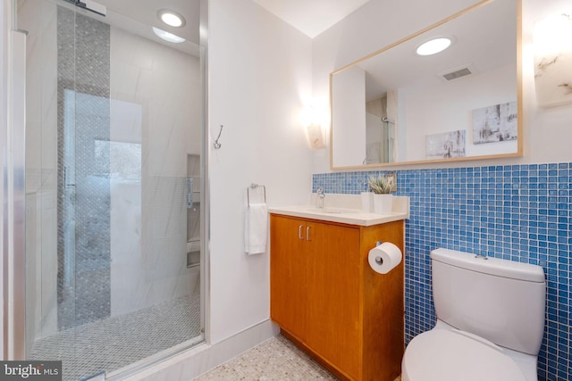 bathroom with visible vents, toilet, vanity, a shower stall, and tile walls