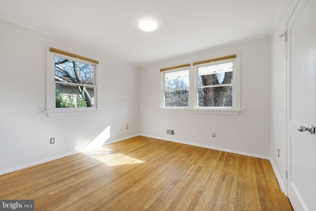 unfurnished bedroom with light wood finished floors, multiple windows, visible vents, and baseboards