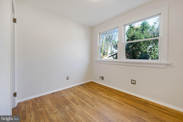 empty room featuring visible vents, light wood-style flooring, and baseboards