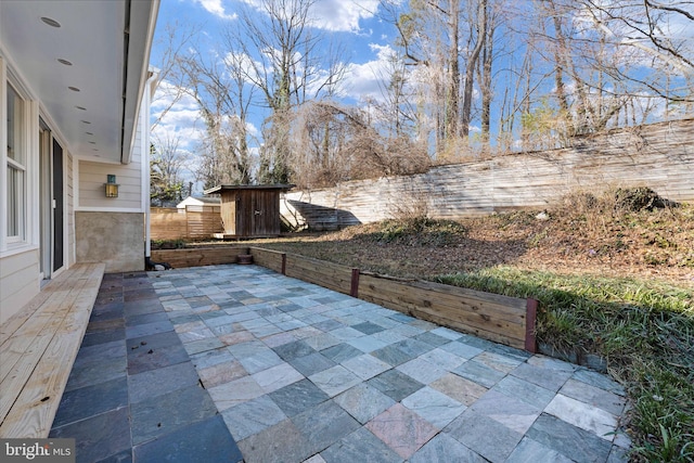 view of patio / terrace with a fenced backyard, a storage unit, and an outdoor structure