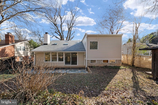 back of property featuring a patio, a shingled roof, a chimney, and fence