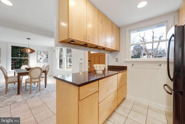 kitchen featuring light tile patterned floors, light brown cabinets, a peninsula, hanging light fixtures, and freestanding refrigerator