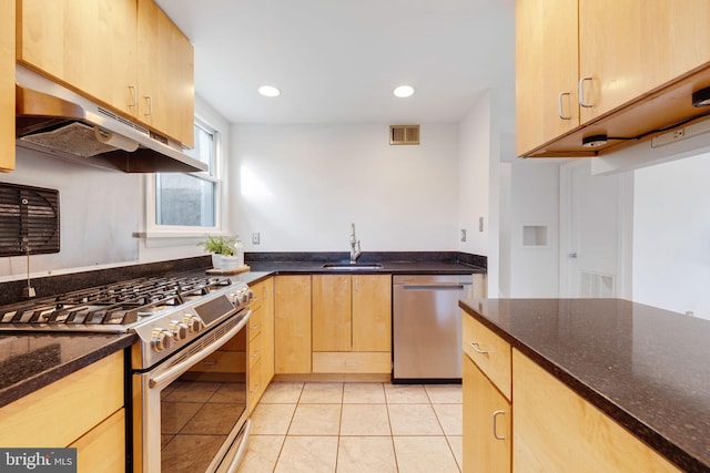 kitchen featuring visible vents, dark stone counters, appliances with stainless steel finishes, light brown cabinets, and a sink