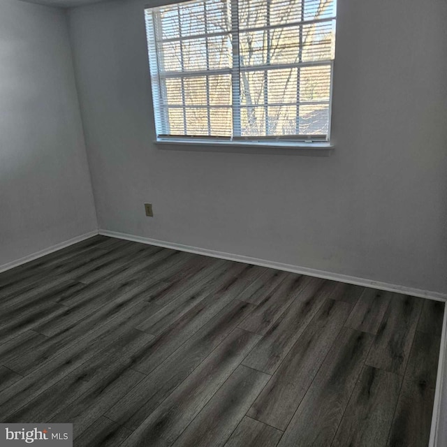 spare room featuring dark wood-style floors and baseboards