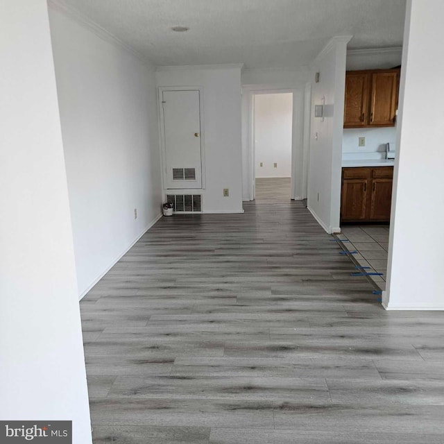 interior space featuring ornamental molding, baseboards, visible vents, and light wood finished floors