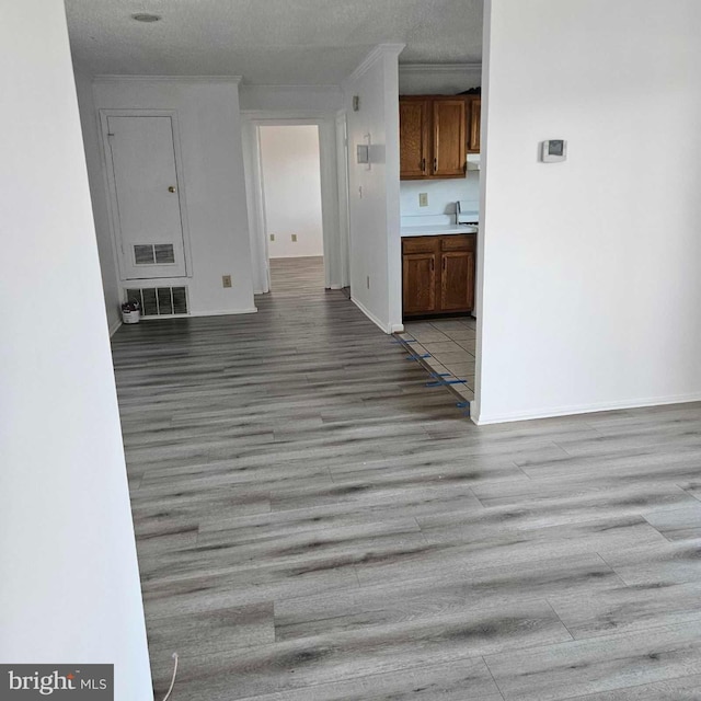 interior space with light wood-style floors, visible vents, and crown molding