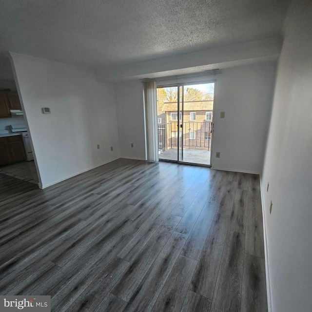 unfurnished living room with a textured ceiling, baseboards, and wood finished floors