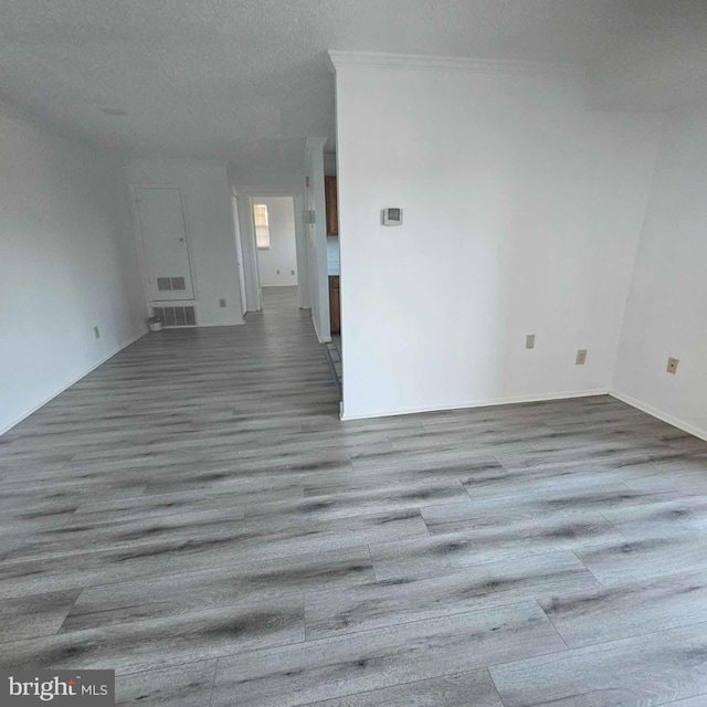 unfurnished living room featuring a textured ceiling, visible vents, and wood finished floors