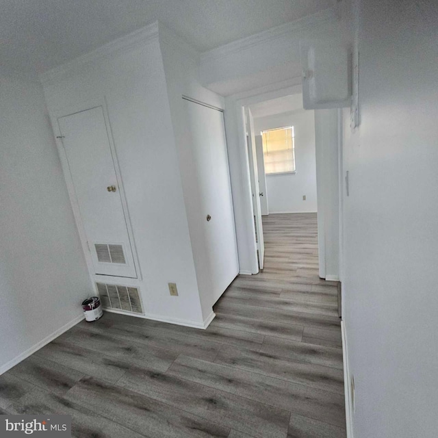 hallway with baseboards, visible vents, and wood finished floors