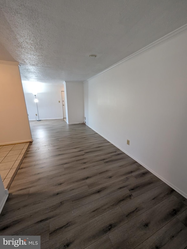 spare room featuring dark wood-style floors, ornamental molding, and a textured ceiling