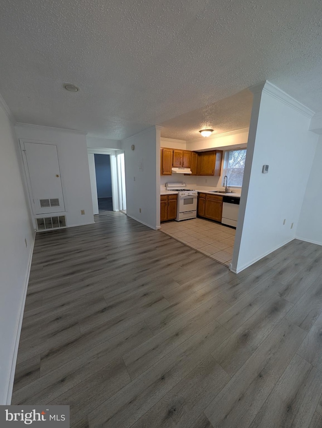 kitchen featuring white appliances, under cabinet range hood, open floor plan, and a sink