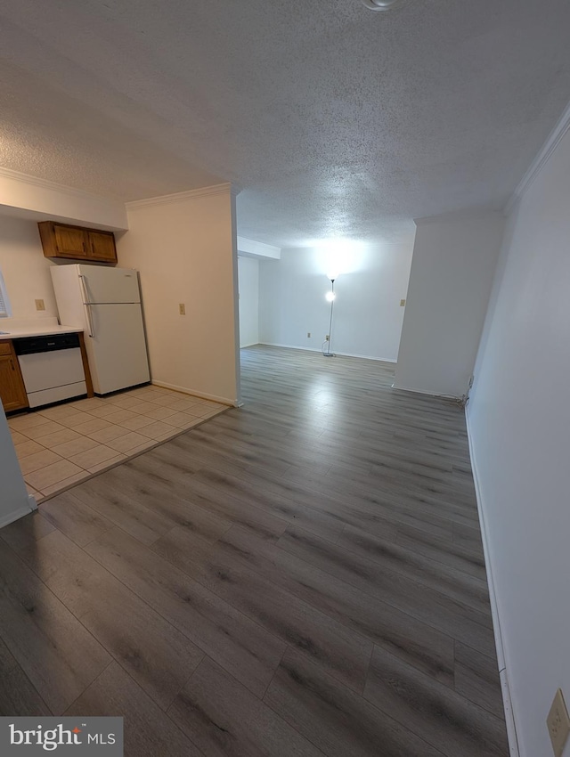 unfurnished living room featuring baseboards, light wood-style flooring, ornamental molding, and a textured ceiling