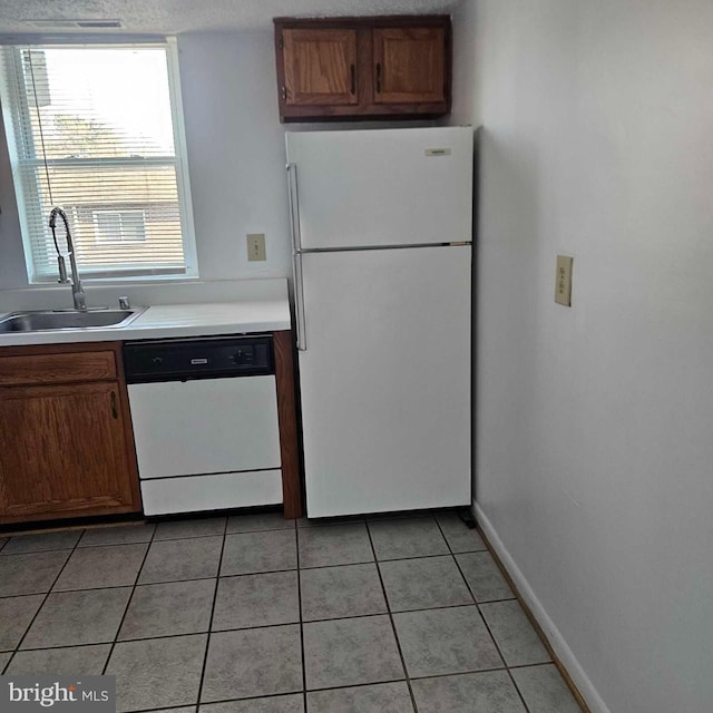 kitchen with white appliances, light tile patterned floors, baseboards, light countertops, and a sink